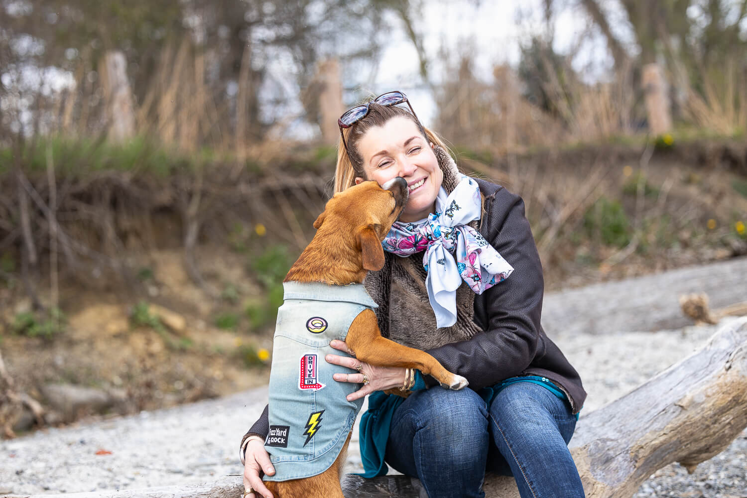 family and pet portrait in Mississauga dog kissing mom in a photoshoot at a beach in Mississauga.