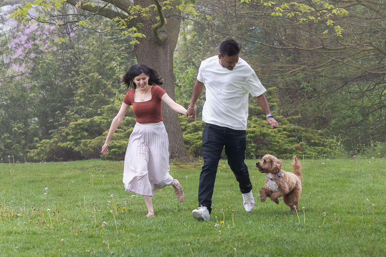 dog and owner photo ideas a candid moment of dog pet parents running with their dog in a dog photo shoot in Oakville